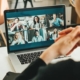 woman uses laptop to video conference with six coworkers