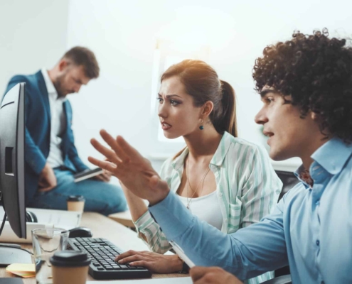 Image of an IT person helping a puzzled business woman with her computer.