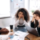 Image of exhausted team members meeting around a table.